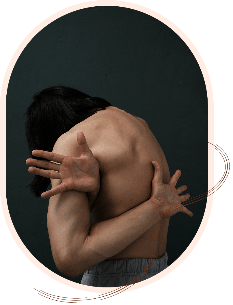 Person with long hair embracing their own back in a dark, moody setting
