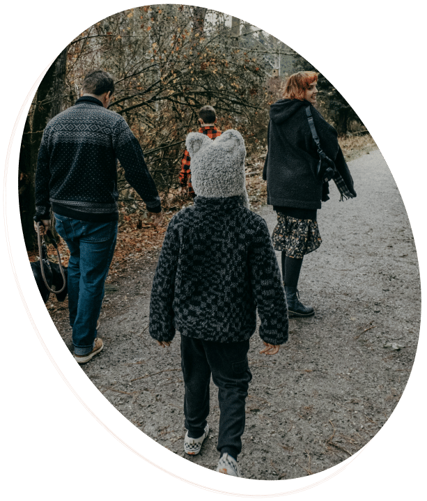 Family walking on a forest path with a dog.