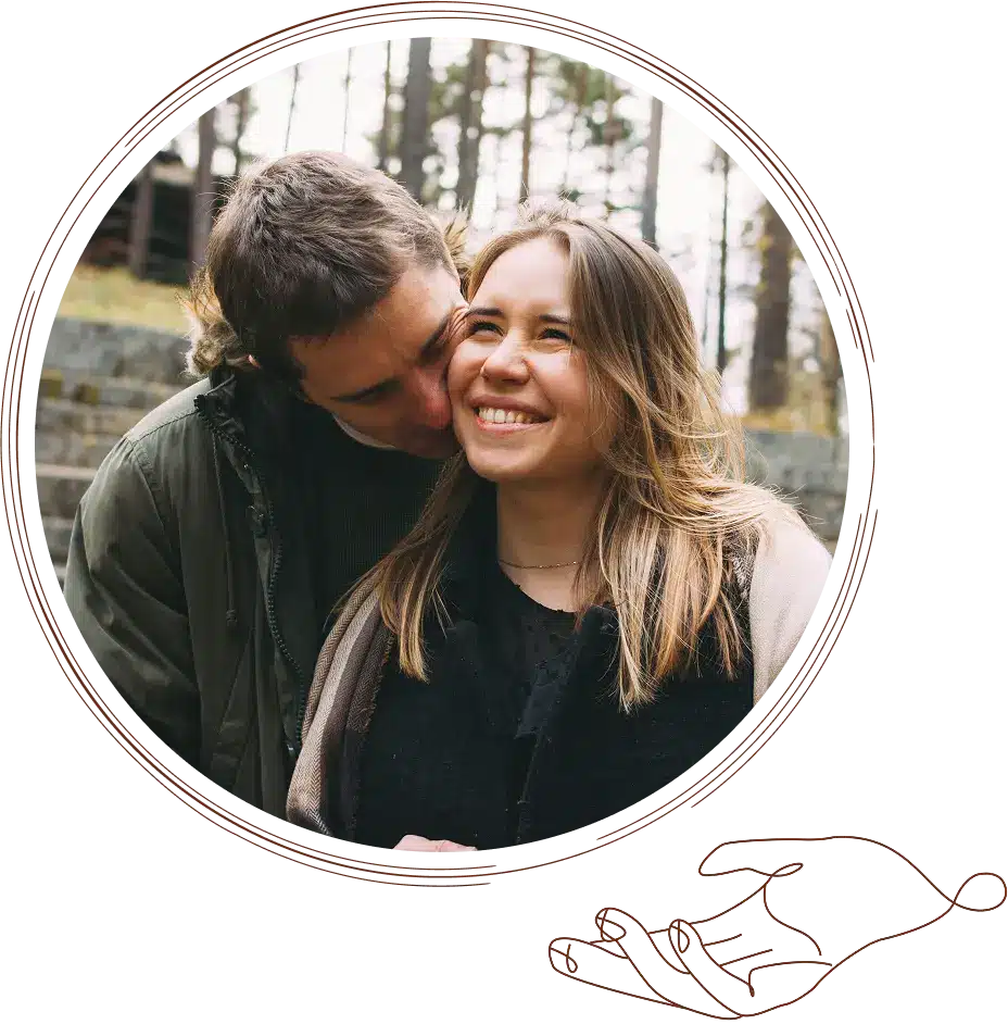 A happy couple smiling and embracing in a natural outdoor setting with trees.