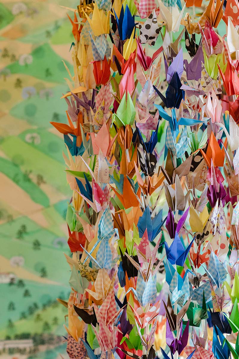 A collection of multicolored origami cranes hanging on strings.