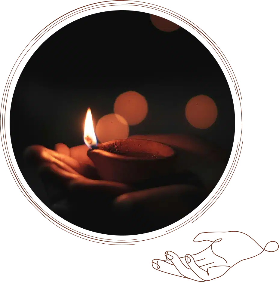 A pair of hands gently cup a lit clay lamp in the dark