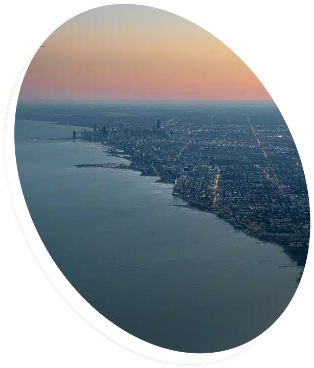 An aerial view of a city skyline on a lake shore at dusk