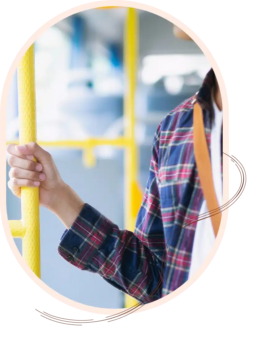 A person wearing a plaid shirt holds onto a yellow pole on a bus.