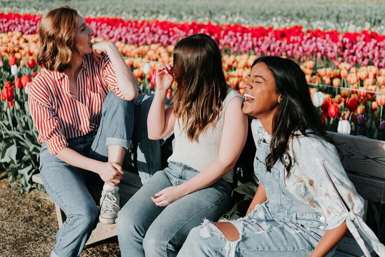 Three women laughing in a tulip field.