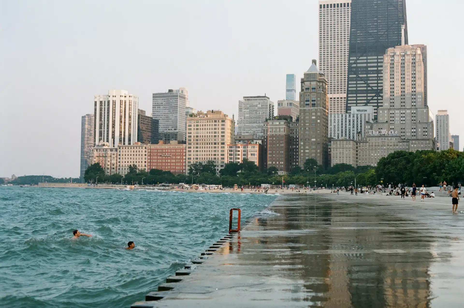 People swimming in Lake Michigan at Ohio Street Beach with the downtown Chicago skyline rising in the background.