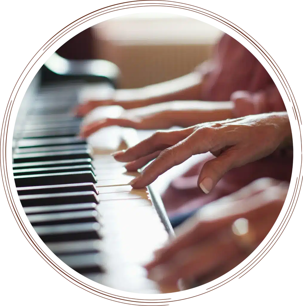 Close-up profile view of multiple hands side-by-side playing the black and white keys of a piano during a lesson or performance.